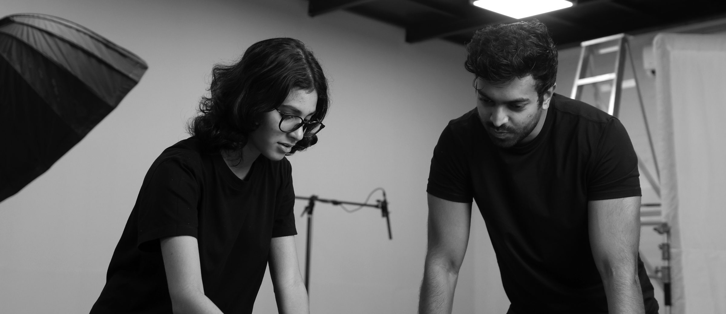 Two people reviewing printed work at a table in a studio