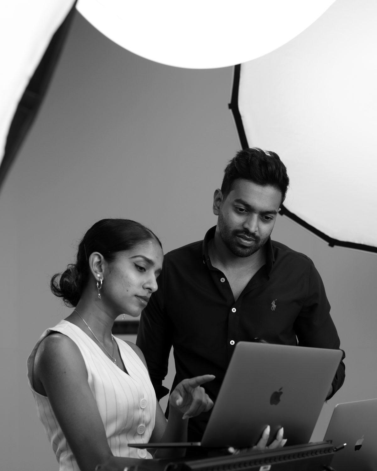 Two people reviewing a laptop together on a studio set